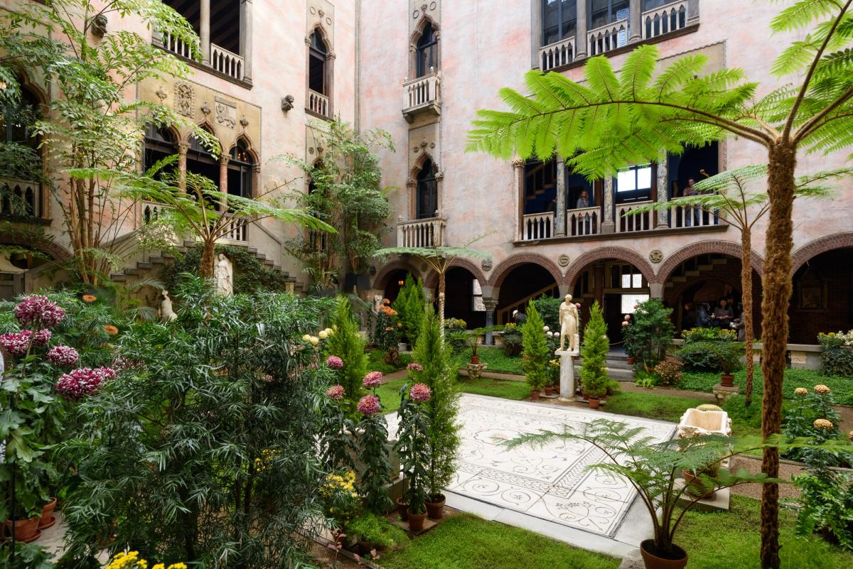 The glass roofed interior courtyard of the Isabella Stewart Gardner Museum, planted and surrounded by Venetian style arcades.