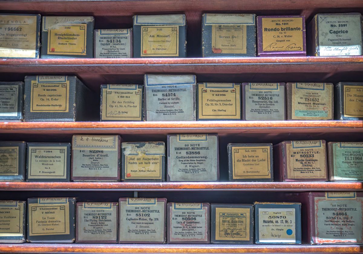 Many piano rolls shelved in their original printed cardboard boxes.