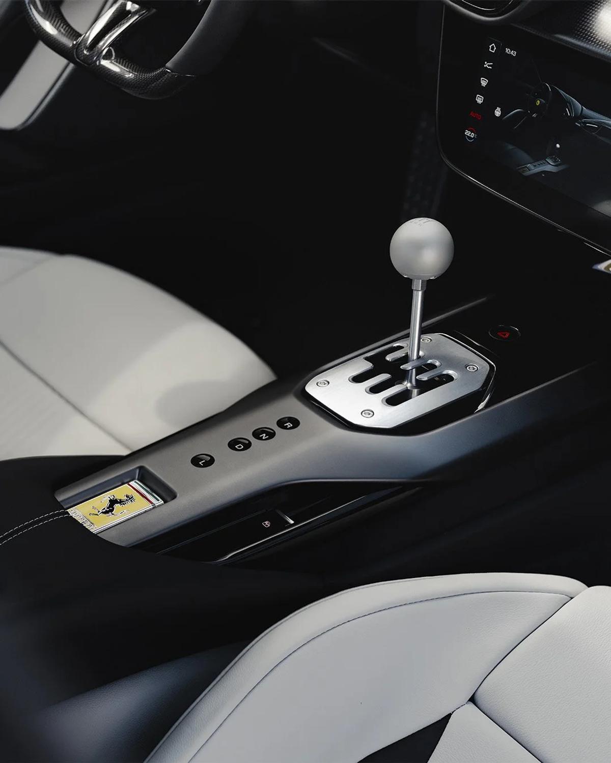 The open gate as semiotic code: the aluminum wand signifies shifting, while the adjacent automatic gear select buttons reveal the digital architecture beneath.