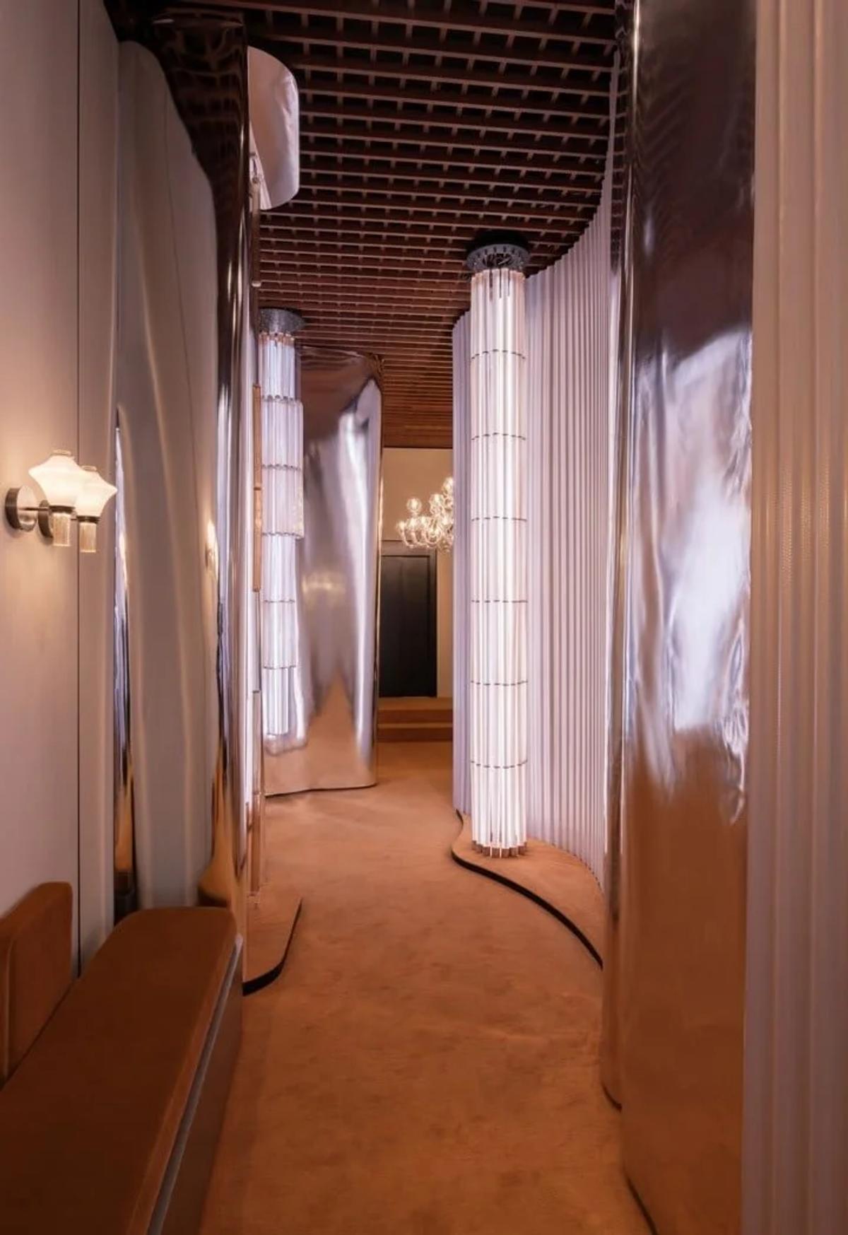 The frictionless, reflective surfaces of modern luxury spaces create an unsettling 'hall of mirrors,' where the distinction between the real and its dazzling representation begins to dissolve.