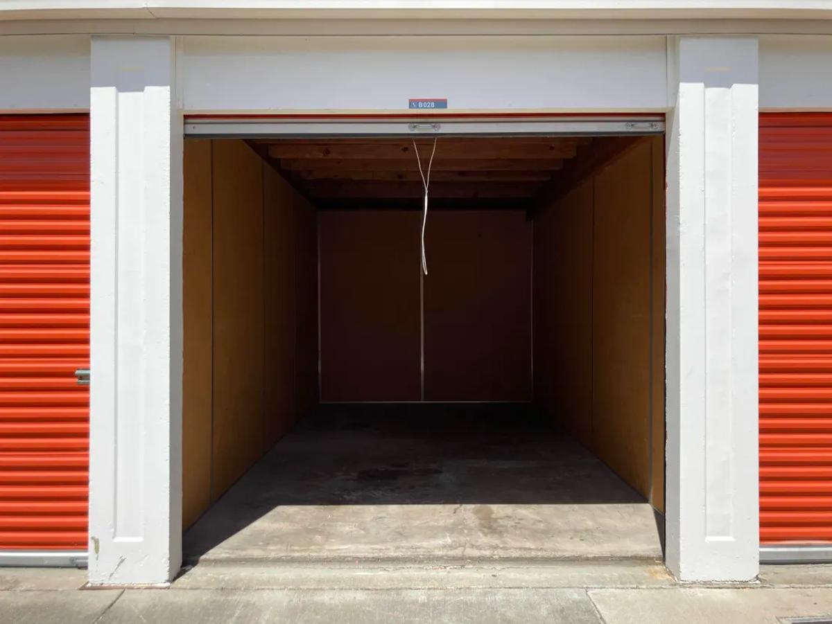 An open, completely empty storage unit with bare walls and a concrete floor.