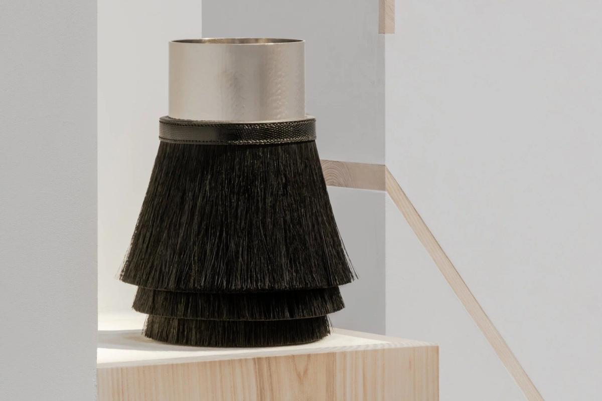  Material Singularity in focus: A vessel from the 2026 collection where hammered metal, lizard leather, and horsehair converge to disclose the biography of the making through raw, tactile density. 