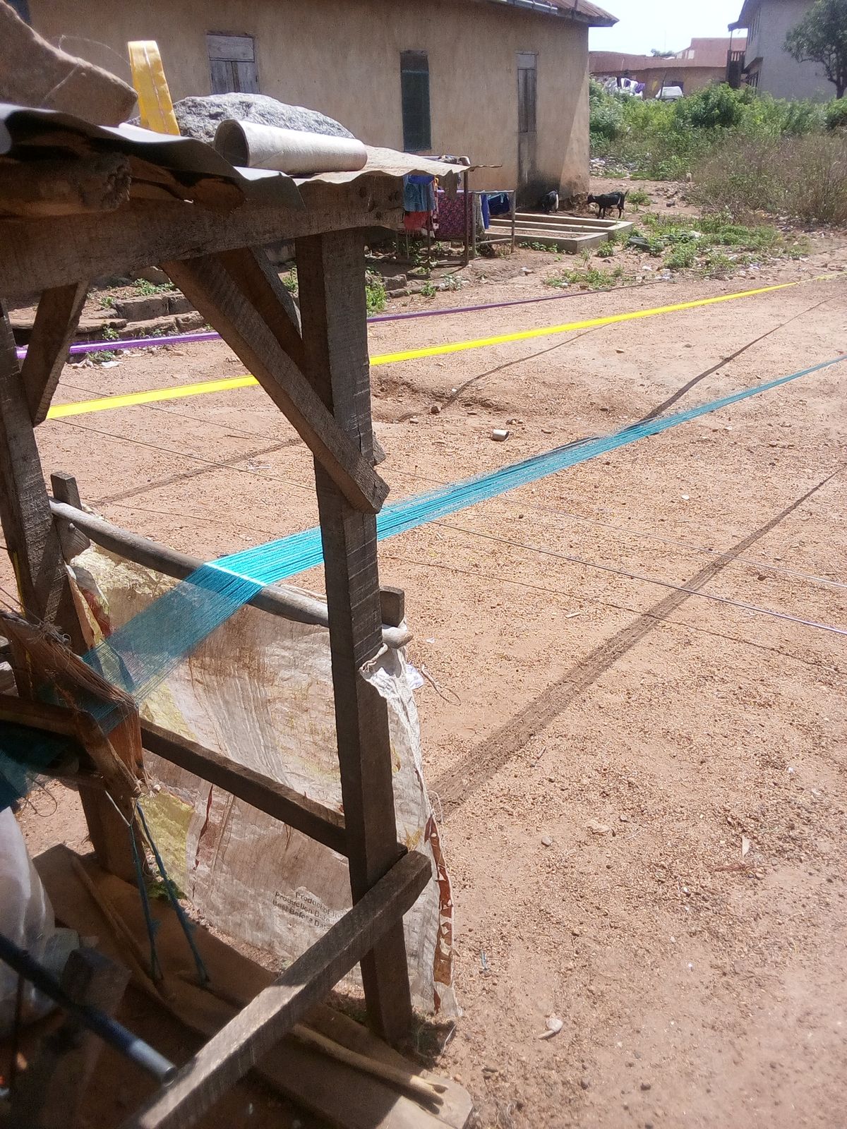 A weaver working at a traditional narrow-band loom, demonstrating the hand-weaving technique underlying West African prestige textile production including sanyan.