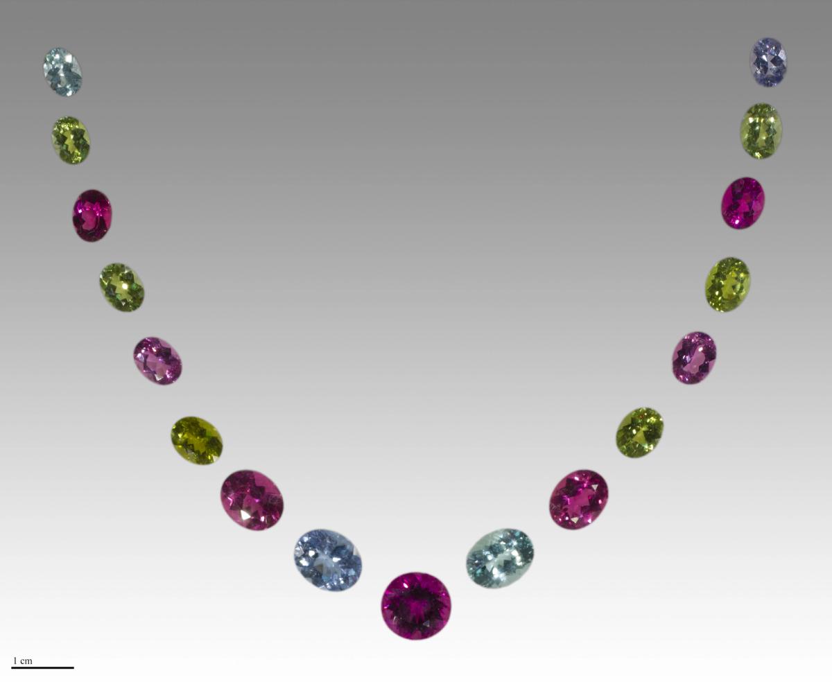 A cut, faceted tourmaline of intense greenish blue, photographed against a dark ground.