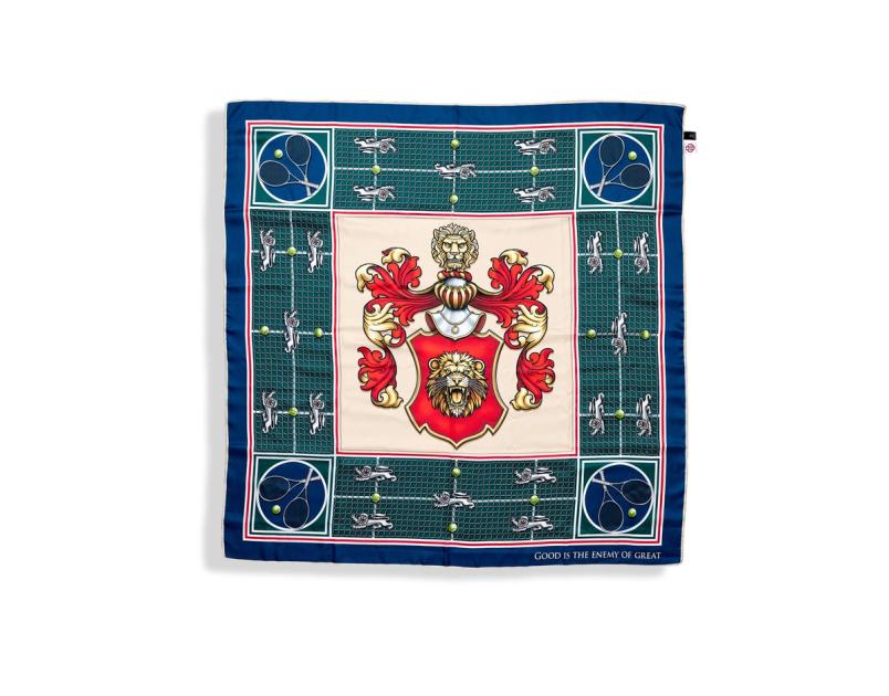 A silk scarf laid flat, its centre panel carrying a red and gold crest with two lions supporting a shield, framed by a green ground and a navy border with small motifs.