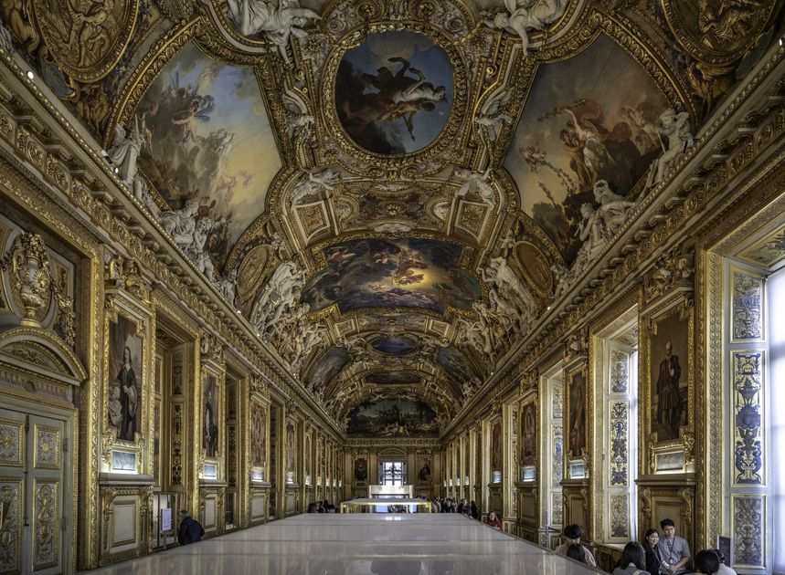 The Galerie d'Apollon at the Louvre, a long barrel-vaulted hall with gilded ceiling paintings and display cases down its length.