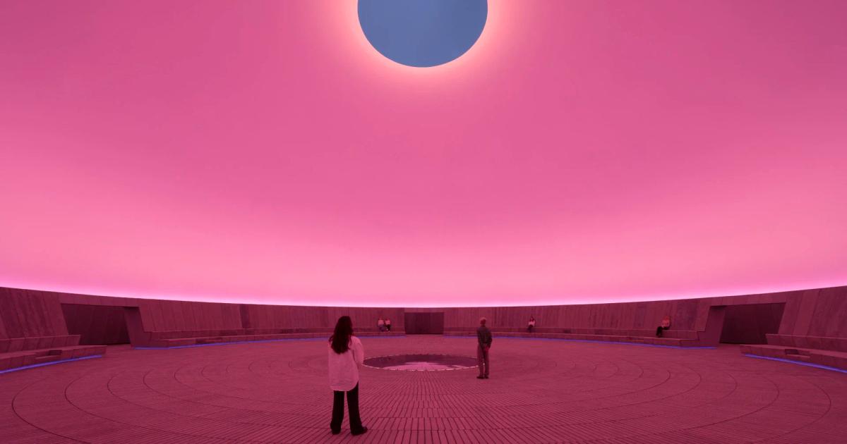 A circular chamber lit deep pink with an oval opening cut through the ceiling to blue sky, two small figures standing on the patterned floor below.