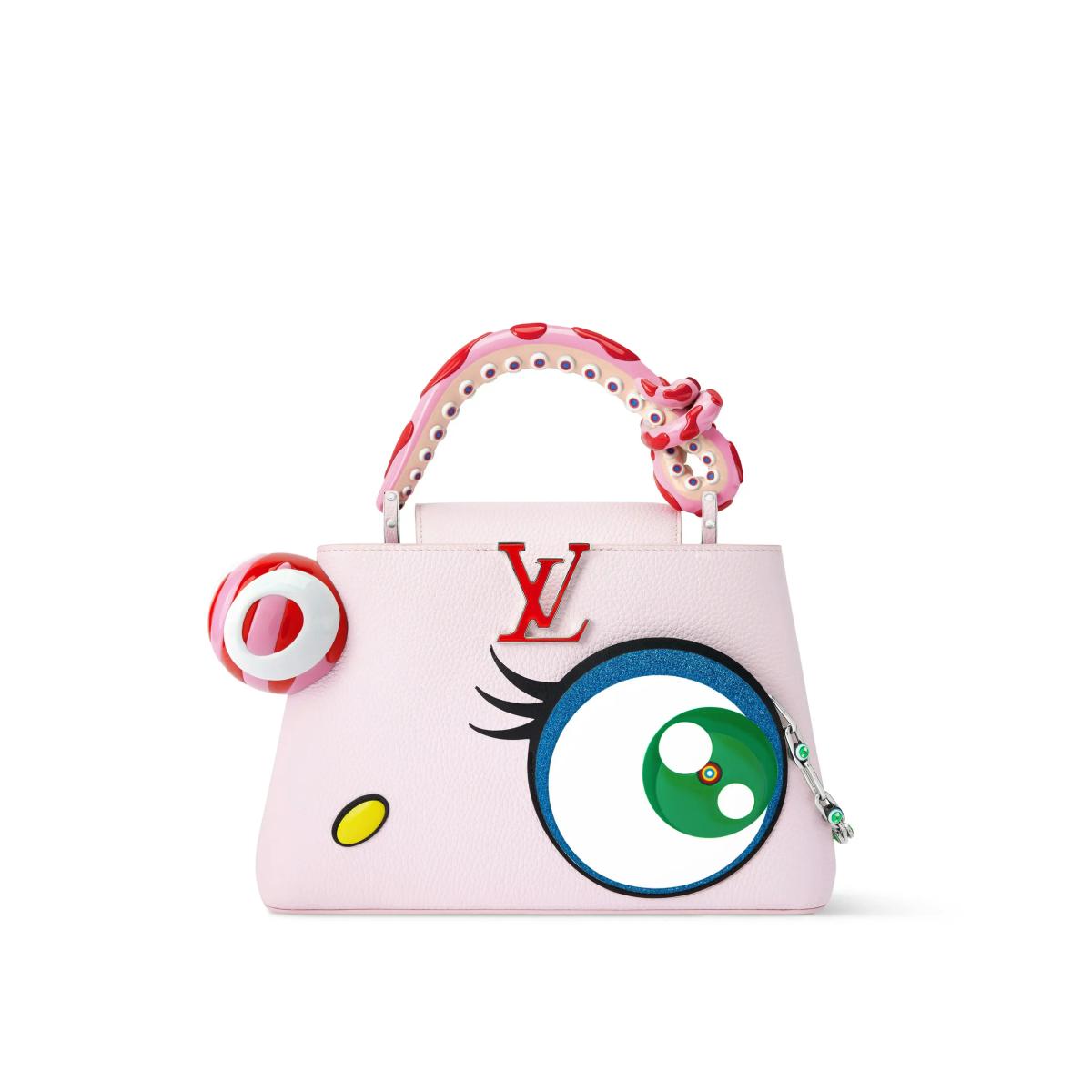 A pale pink structured handbag decorated with an oversized cartoon eye and lashes, a red target shape at one side and a studded red and white handle.