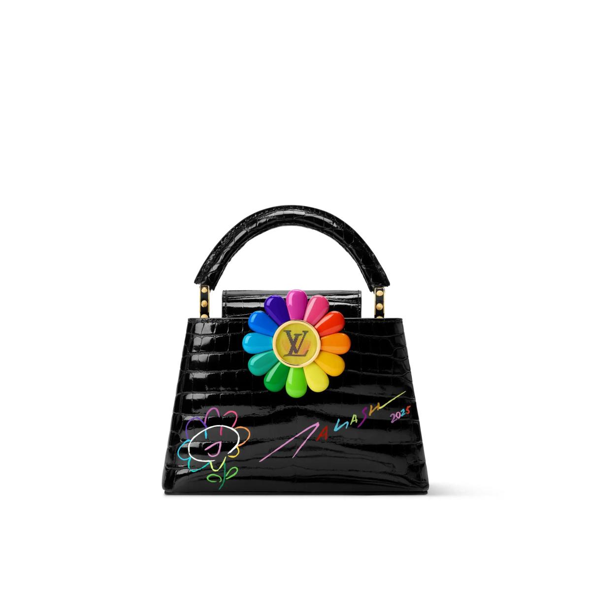 A black crocodile skin top handle bag with a large multicoloured daisy fixed to the front, the flower centred on a gold monogram and outline drawing beside it.