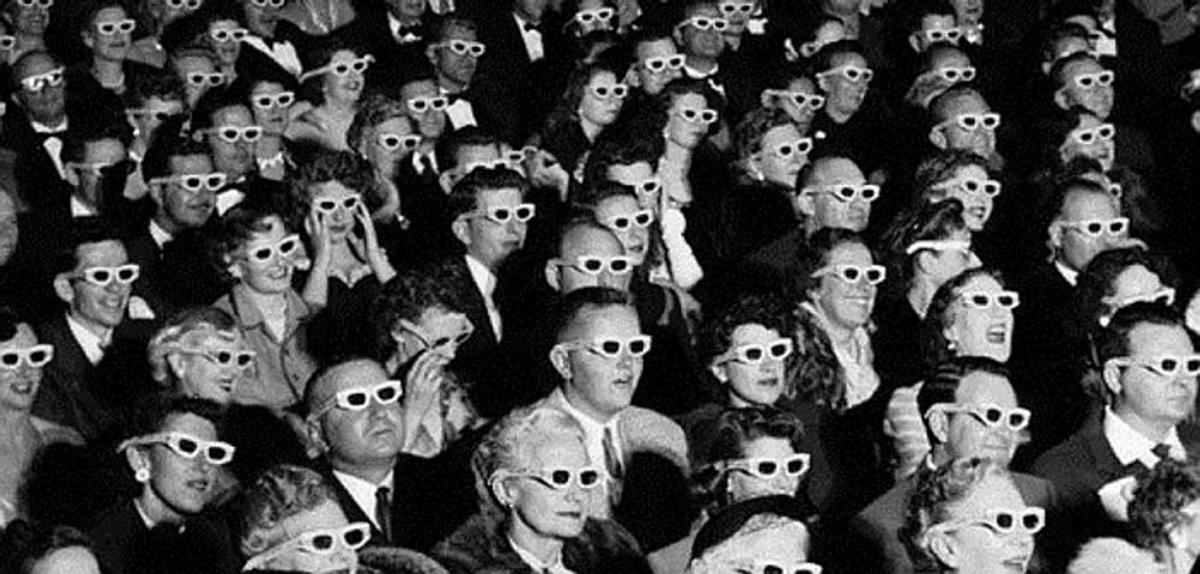 A black and white photograph of a packed cinema audience seated in rows, every person wearing paper 3D glasses and facing the screen.