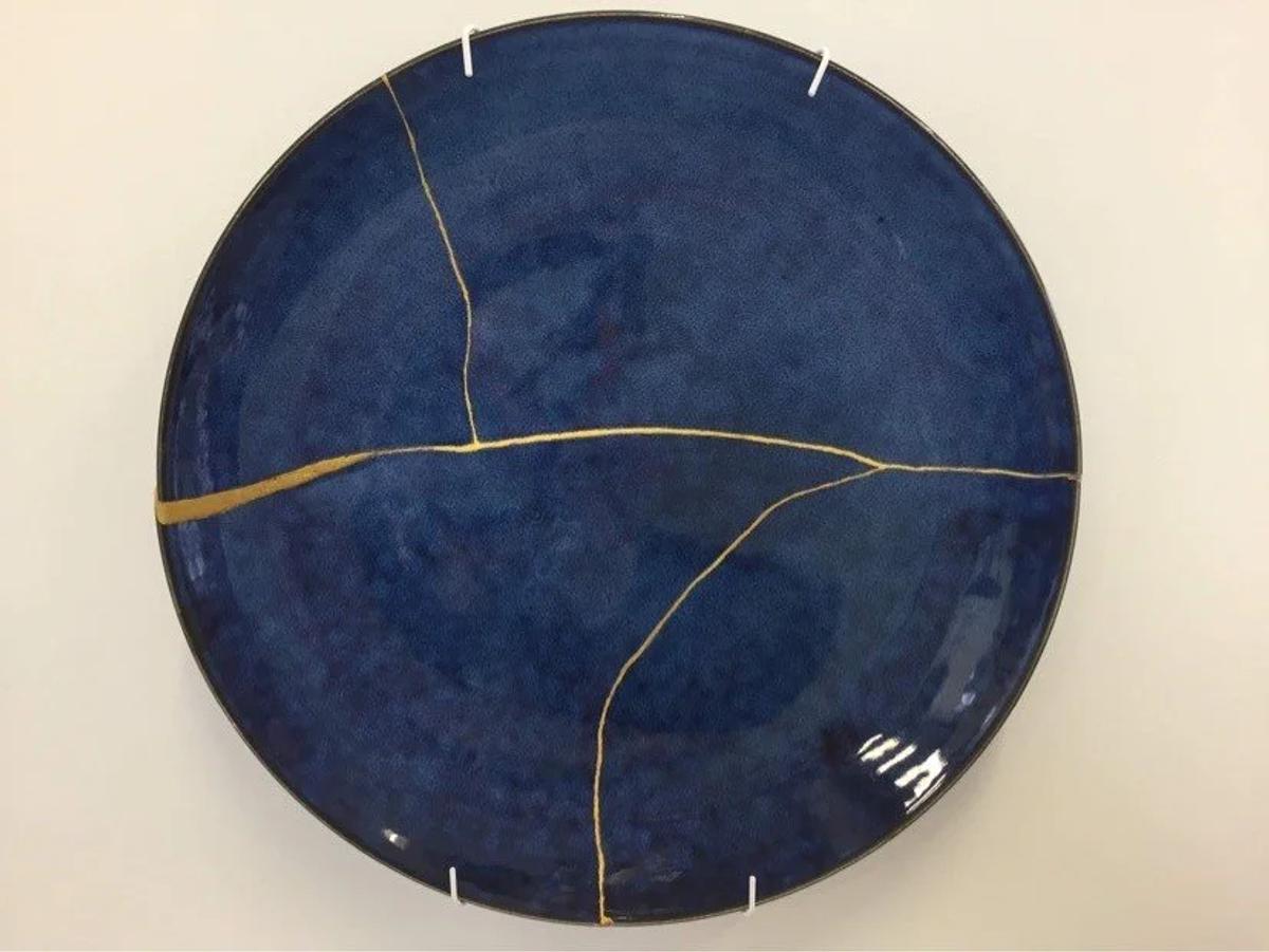 This kintsugi piece embodies the Japanese aesthetic of shibui. The subtle, understated elegance of the deep blue plate is enhanced, rather than diminished, by the visible golden repairs. The gold lines celebrate the object's history and imperfections, turning its flaws into a source of beauty that is both natural and quietly profound.