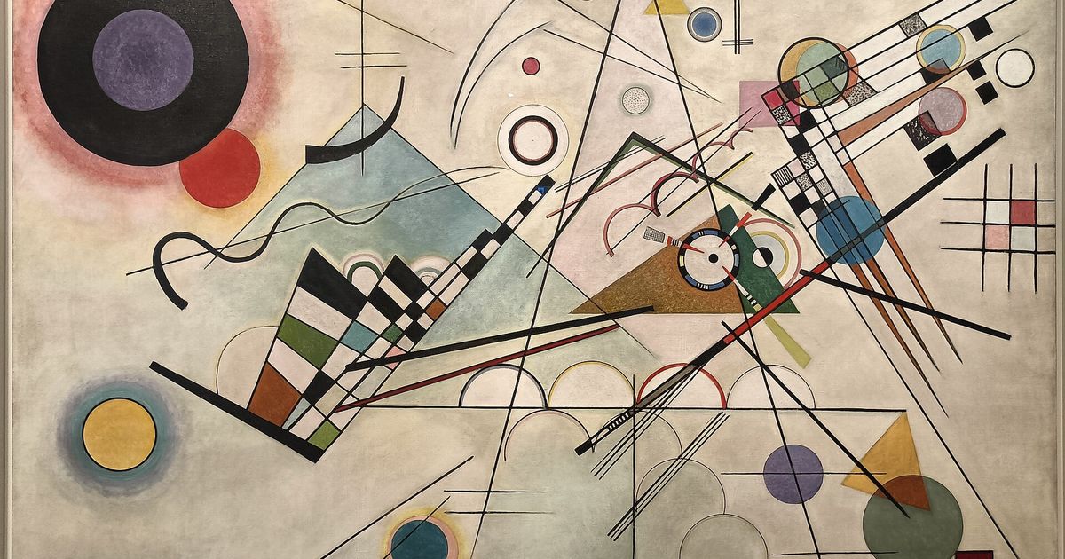 A large abstract canvas on a pale ground covered with circles, triangles, grids and long ruled lines in black, blue, yellow and red.