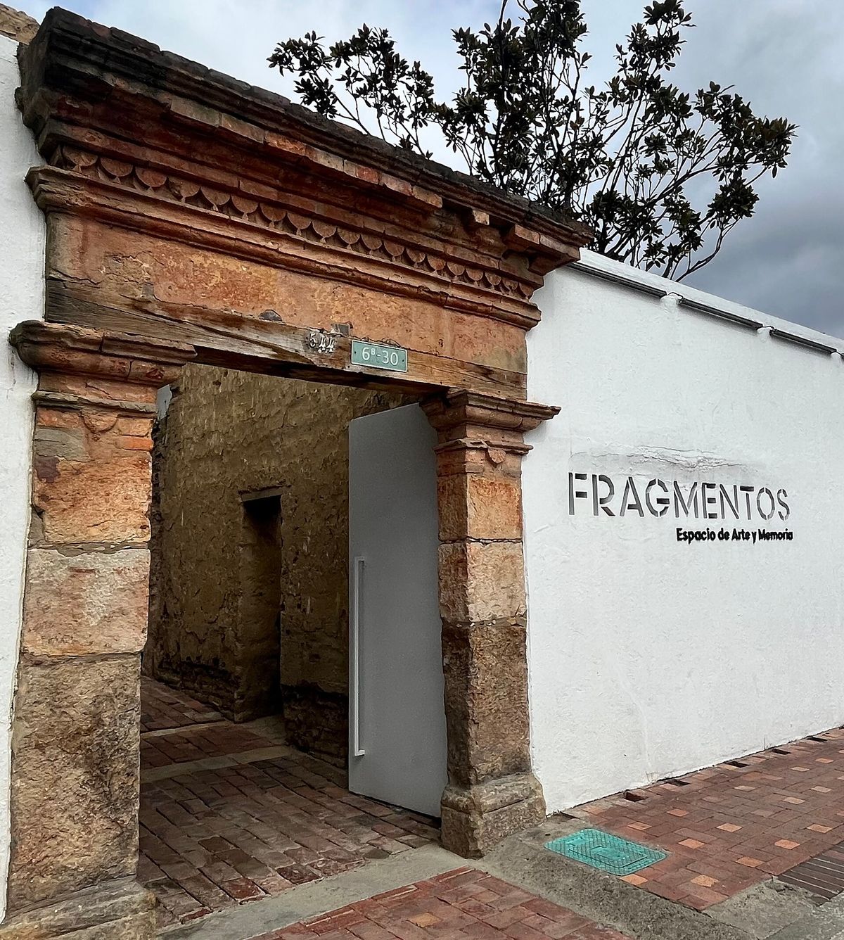 The entrance to the Fragmentos space in Bogota, a doorway in a plain wall beside preserved ruins.