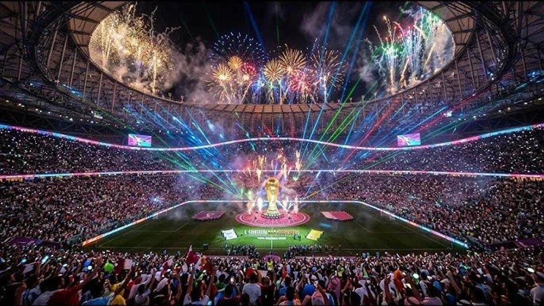 A packed stadium at night during a closing ceremony, fireworks and coloured laser beams above the pitch and a lit stage at the centre of the field.