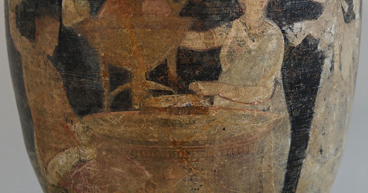 A tall footed ceramic vase with a gilded moulded rim, painted with standing figures at an altar in muted reds and browns on a pale ground.