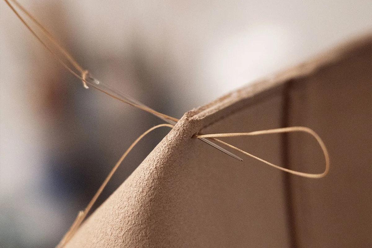 Traditional hand-stitching in haute maroquinerie: An absolute manifestation of Labor Density, where the irreversible trace of the artisan's hand anchors an object's genuine Material Singularity against speculative hollowing.