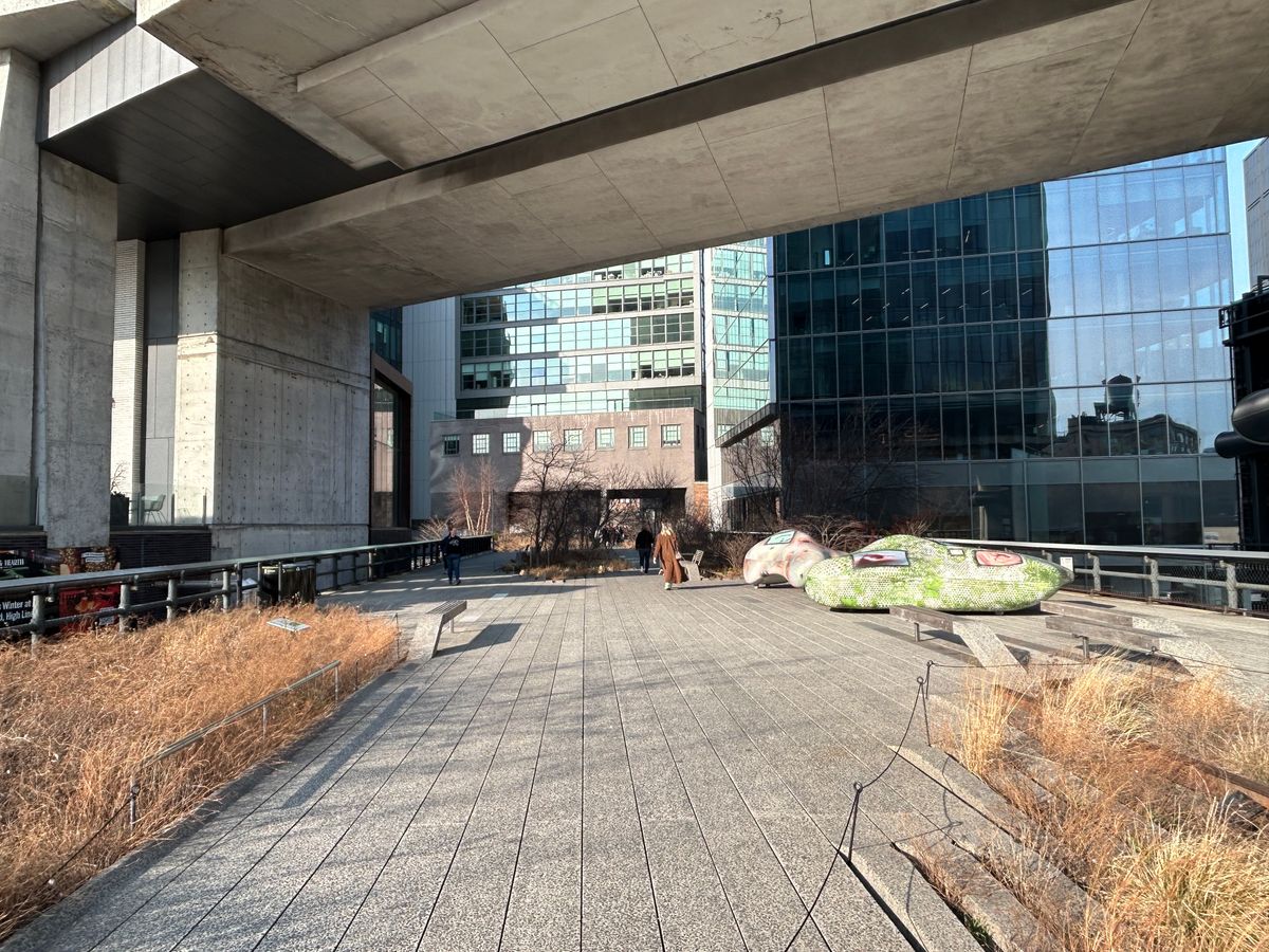 A view along the High Line elevated park looking north toward Hudson Yards, with the luxury towers of the development visible at the horizon