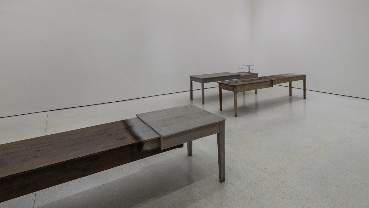 An installation view of the Unland series. By joining disparate table pieces, the domestic utility is structurally blocked. The object's new function is to act as a memorial for fragmented lives, achieving Commemoration and Repair.