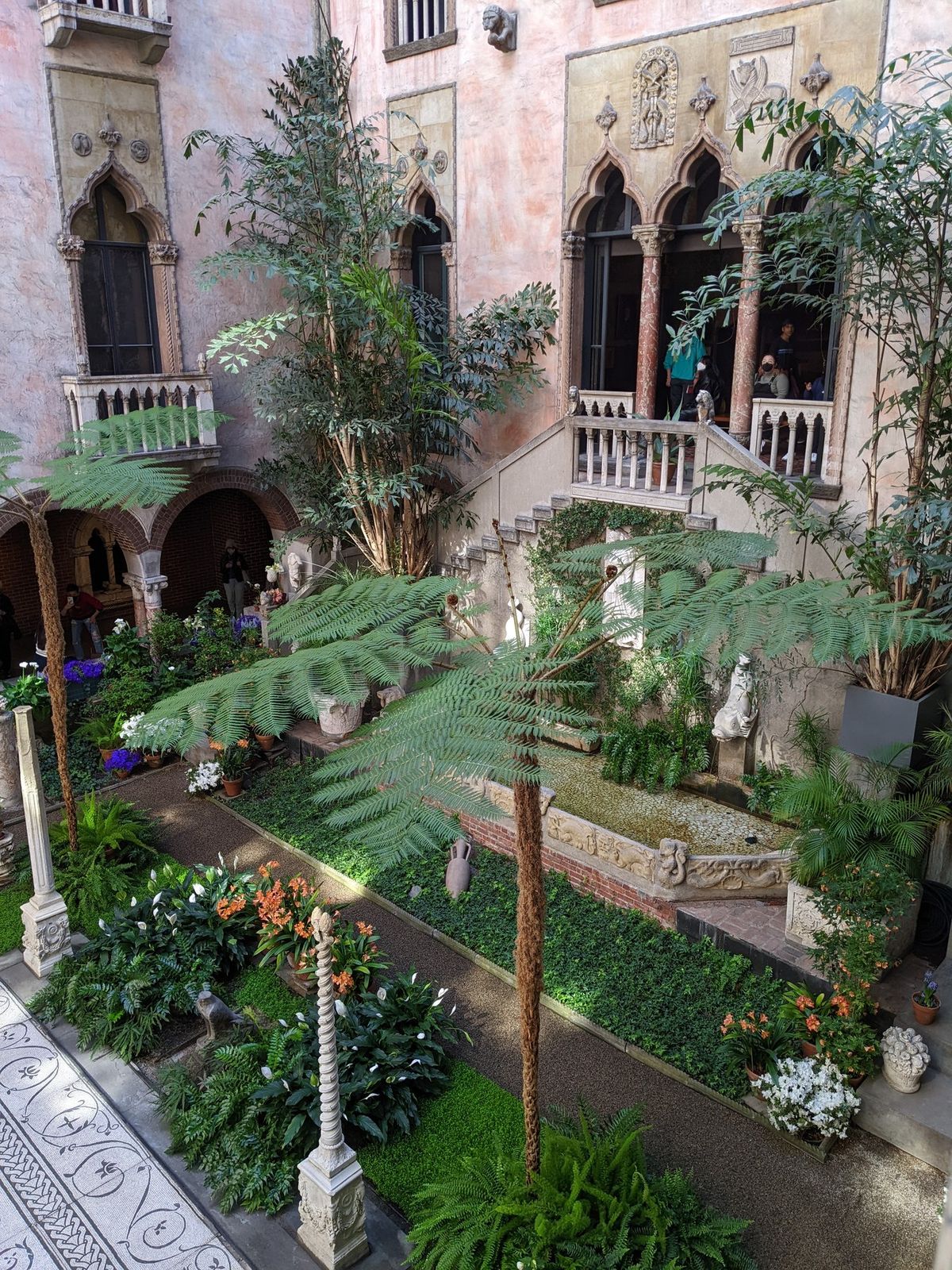 The glass-roofed courtyard garden of the Isabella Stewart Gardner Museum in Boston, with arched galleries rising on each side.