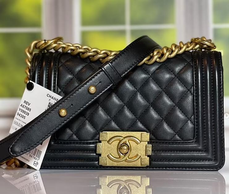A black quilted leather flap bag with a heavy chain strap and a brushed gold clasp, a resale authentication tag hanging from the handle.