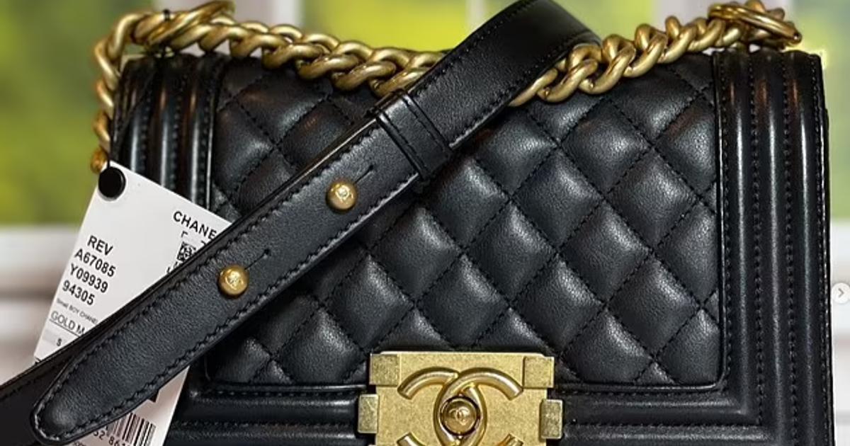 A black quilted leather flap bag with a heavy chain strap and a brushed gold clasp, a resale authentication tag hanging from the handle.