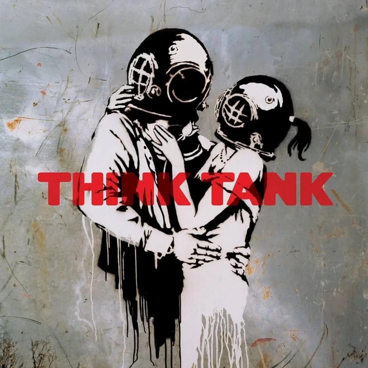 A stencilled mural of two figures in old diving helmets embracing, with the words Think Tank sprayed in red across the weathered grey wall behind them.