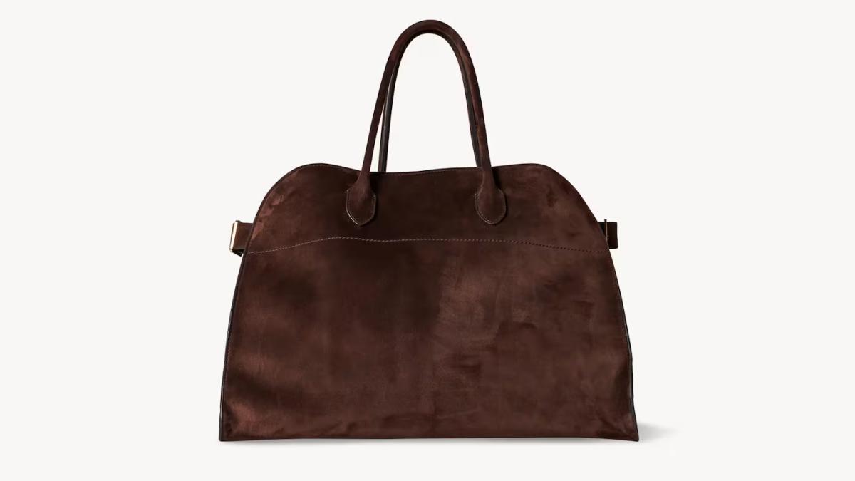 A large soft brown suede tote with rolled leather handles, photographed against a plain pale background.