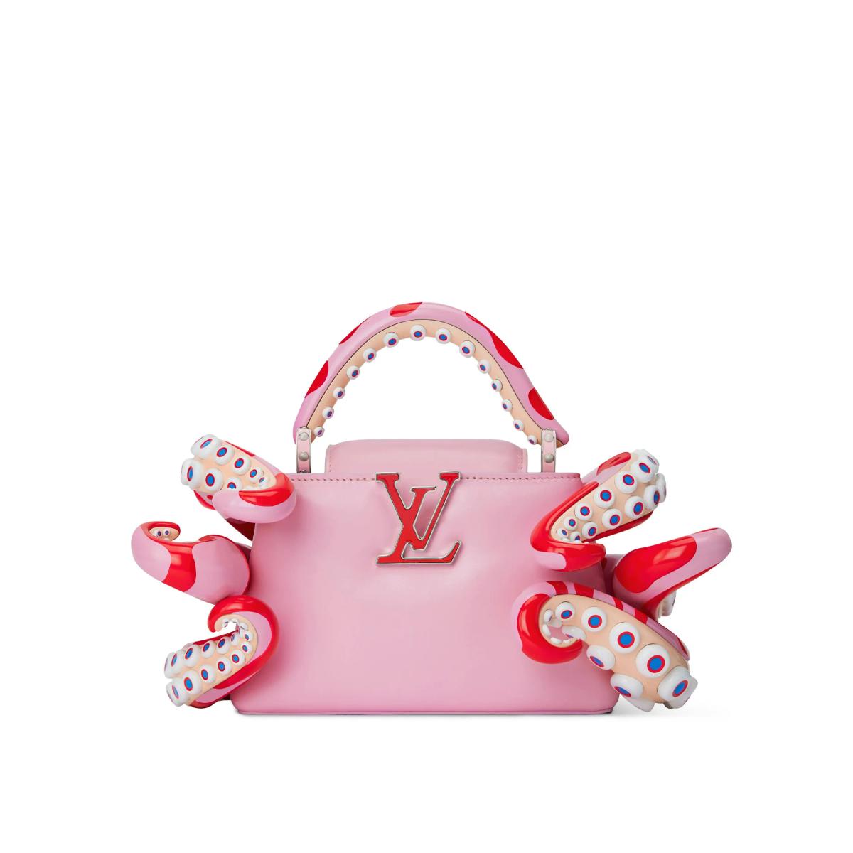 A pink structured handbag with a raised monogram on the front, wrapped by moulded red and white spotted tentacle forms curling over its sides and handle.