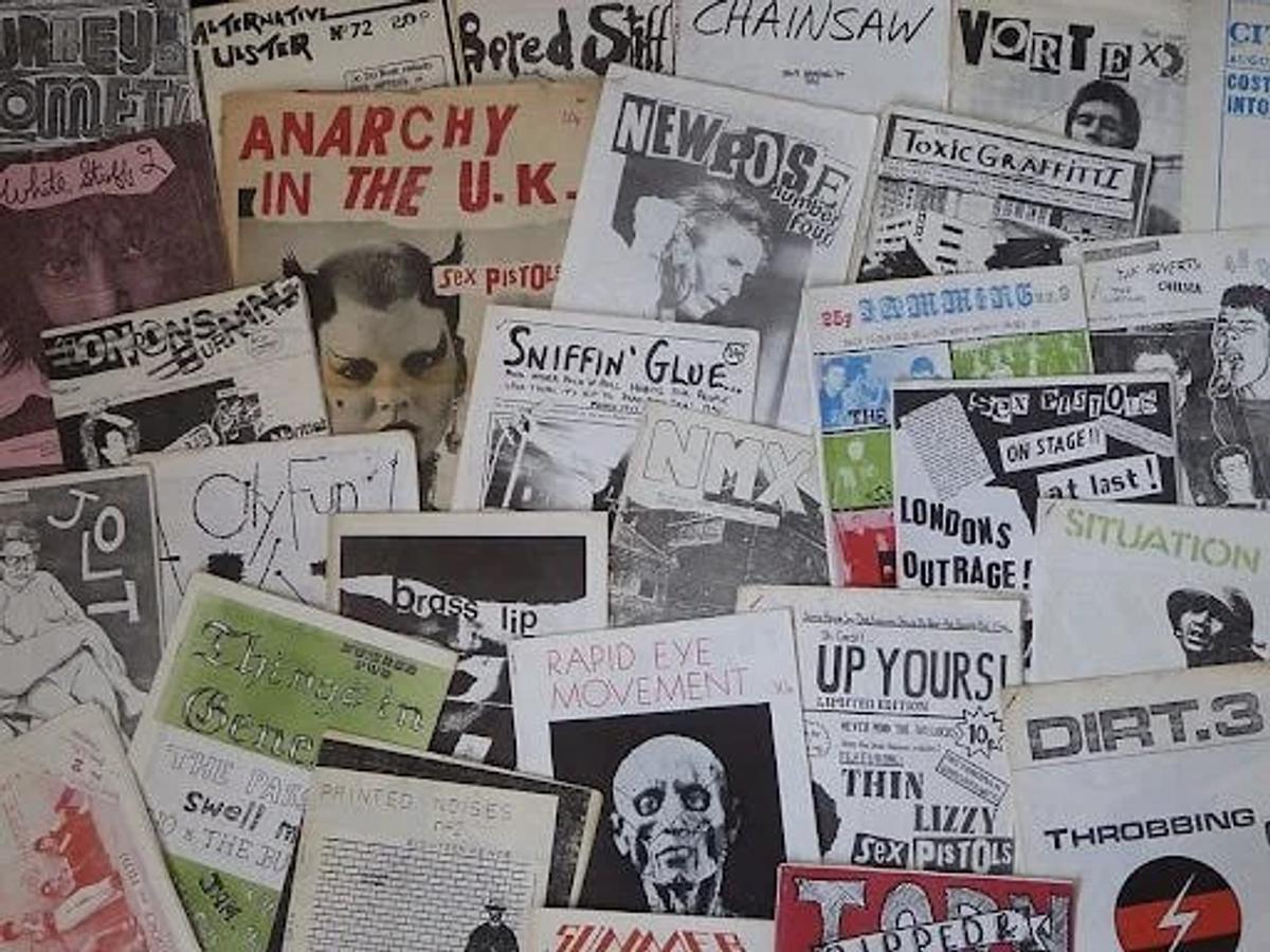 A dense overlapping spread of punk fanzines and printed pages with hand lettered headlines, photocopied images and torn edges.