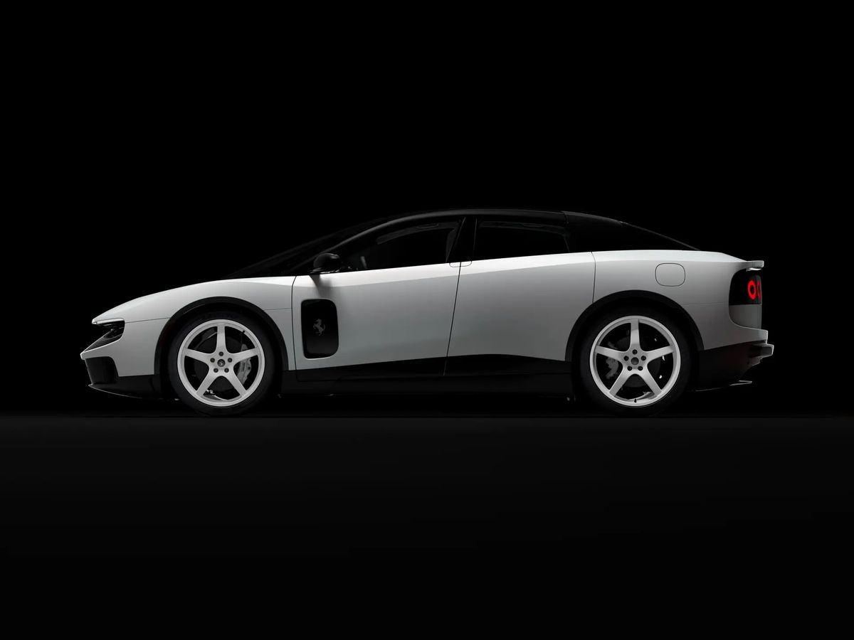 Ferrari Luce Chassis 0 in side profile against black, showing the four door silhouette of the electric grand tourer with a black roof and white five spoke wheels.
