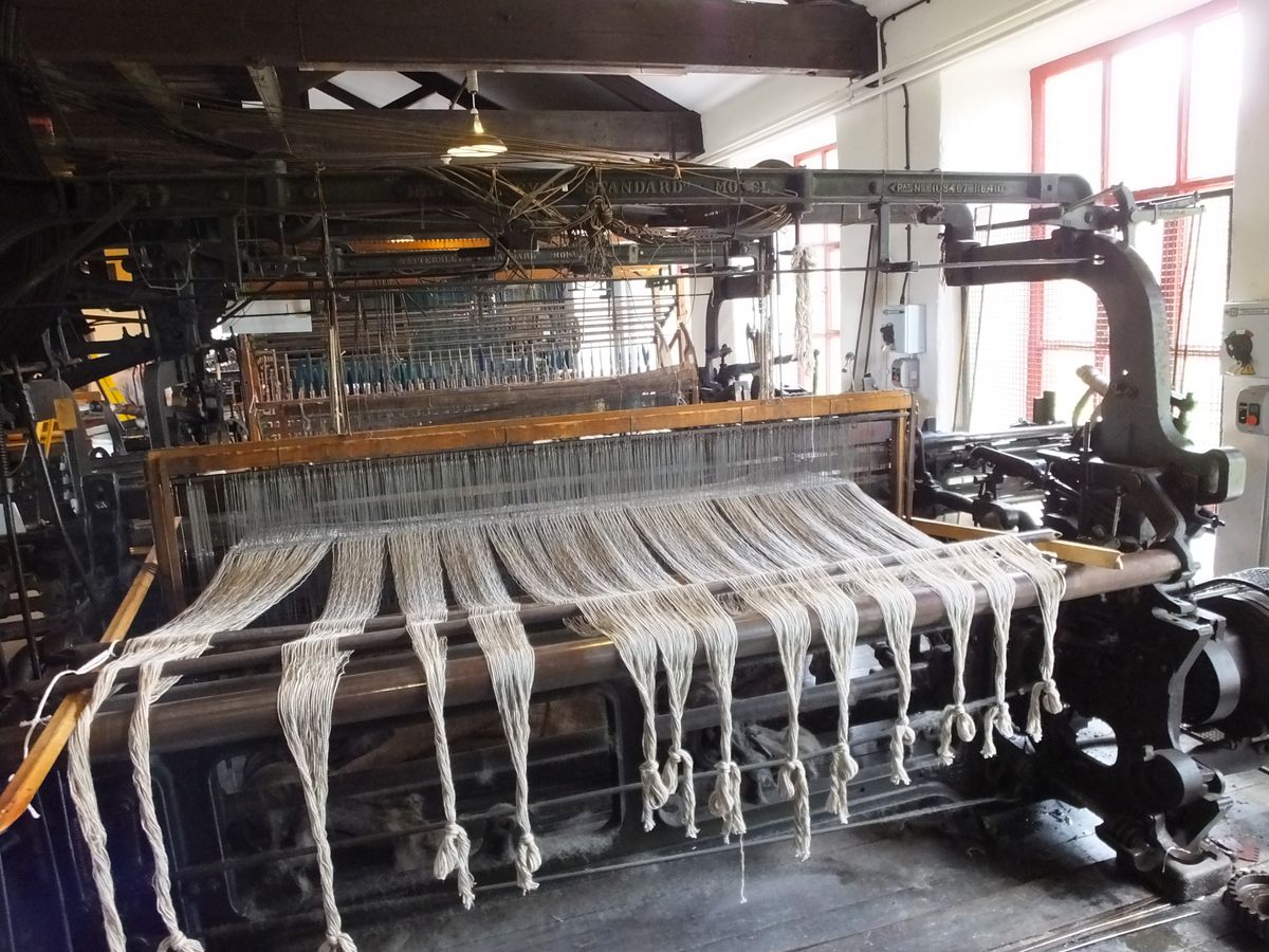A Hattersley standard power loom preserved in a museum, its frame, healds and shuttle race visible.