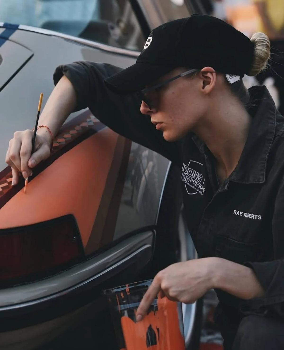 Witnessed Origination: Rae Roberts executing the Al Sadu livery concept by hand at the Icons of Porsche festival in 2023, demonstrating the raw creative labor later institutionalized by the corporate apparatus.