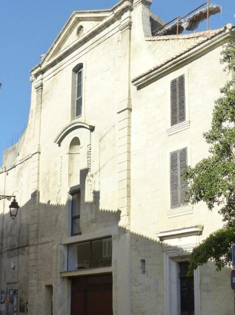 The stone facade of the former Sainte-Croix church in the Roquette district of Arles, seen from the street.