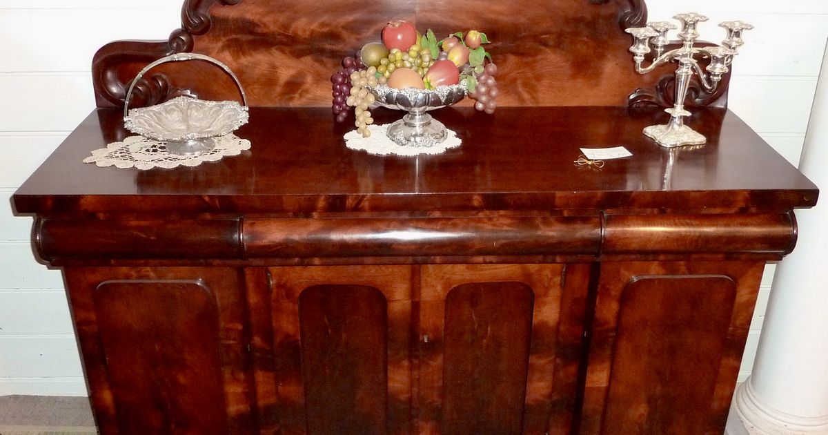 A Victorian mahogany sideboard with carved detailing and a mirrored back, standing against a wall.