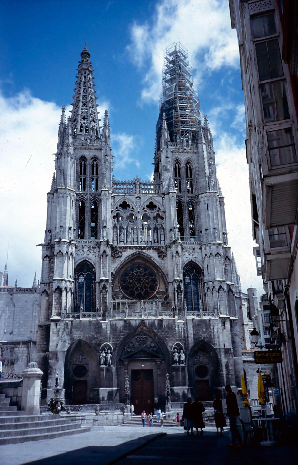 Burgos Cathedral encased in scaffolding during restoration, the stone facade visible behind a metal framework.