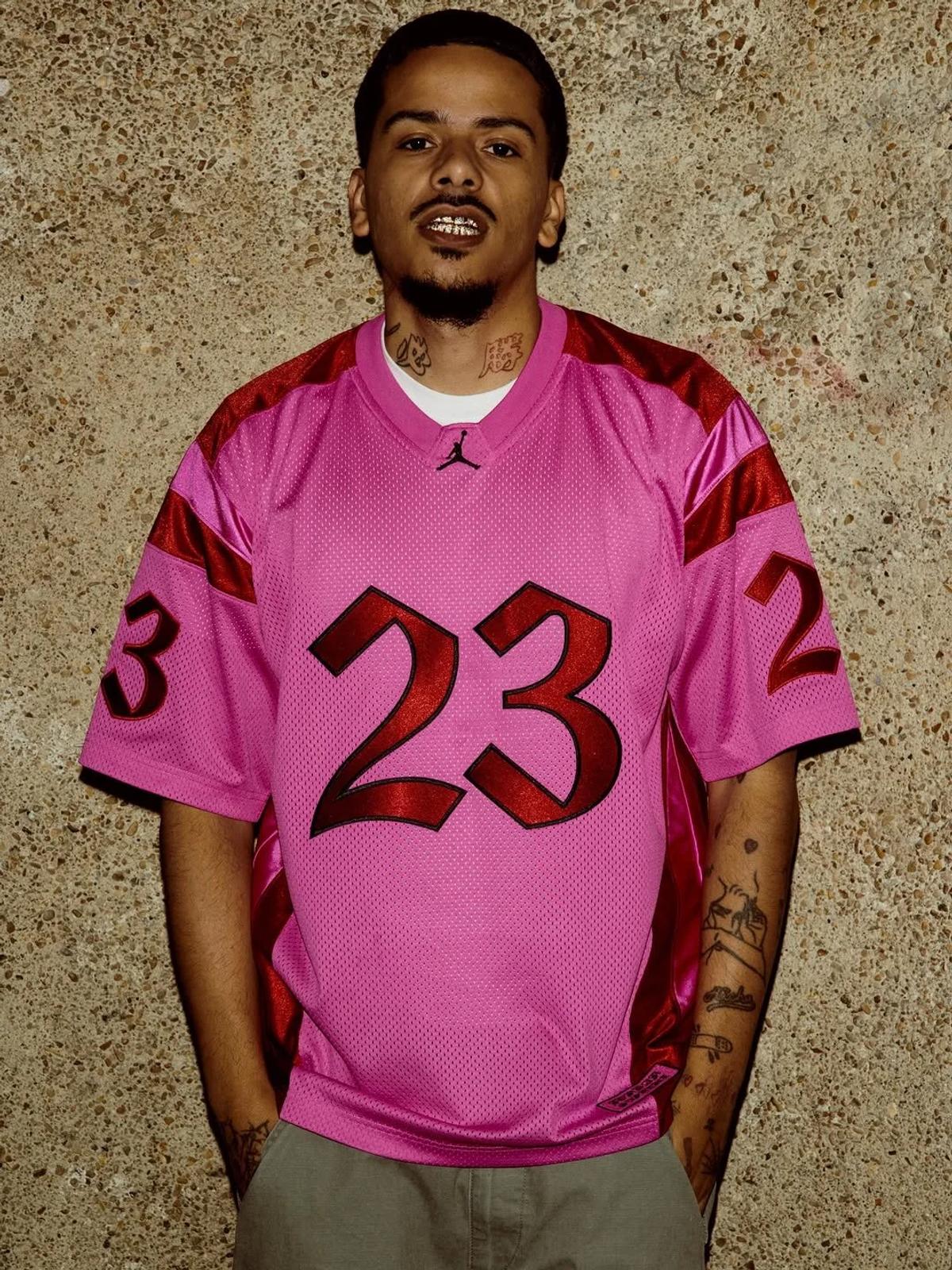 The Fire Pink mesh jersey displaying large numerals rendered in a stylized, bold script; a prime example of the collection's compressed semiotics, trading historic subcultural weight for high-velocity speculative capital.