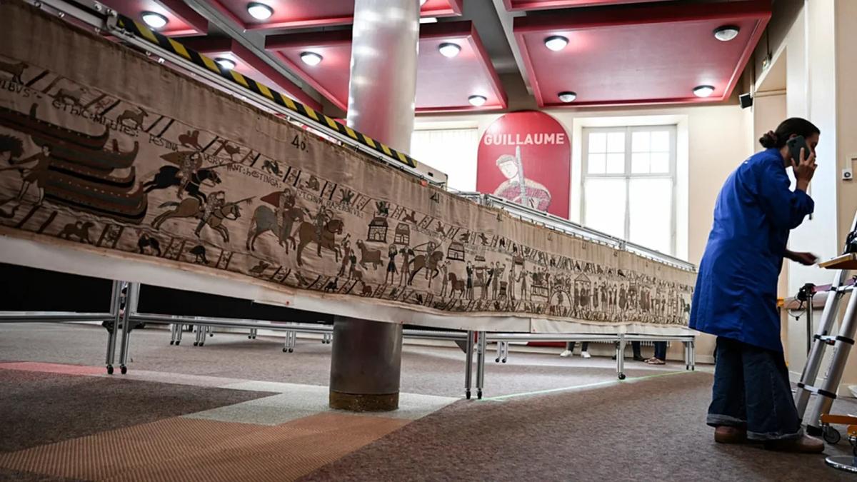  The material reality of handling a nine-century-old sovereign object: specialists examine the structural integrity and linen condition of the Bayeux Tapestry ahead of its monumental flat-display installation. 