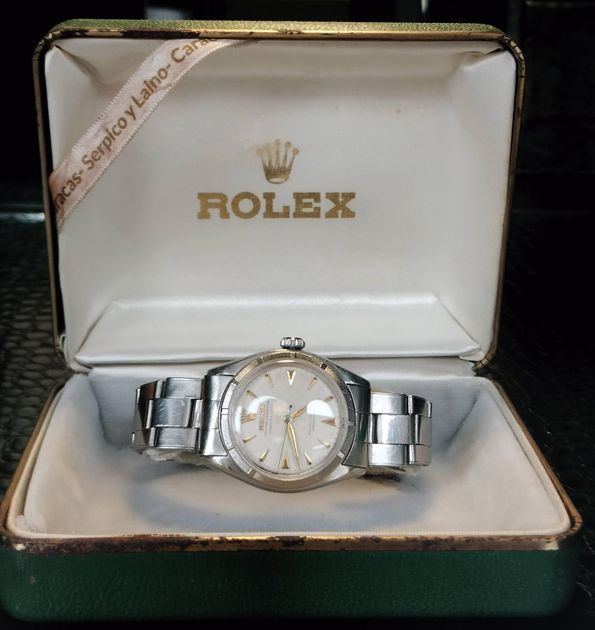 A steel Rolex Oyster Perpetual lying in its original green and cream presentation box, the lid gilt-stamped with the Rolex crown, a printed ribbon across it reading Caracas, Serpico y Laino.