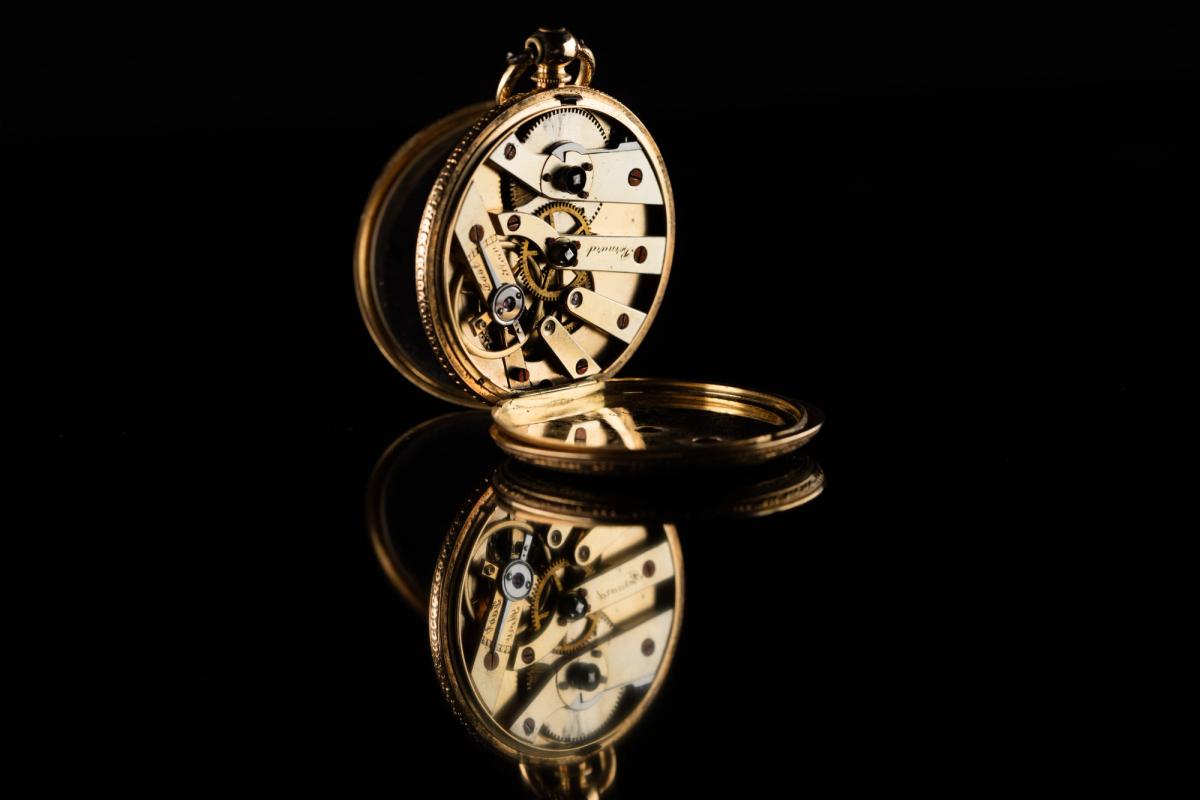 An antique pocket watch displayed beside its fitted presentation box.