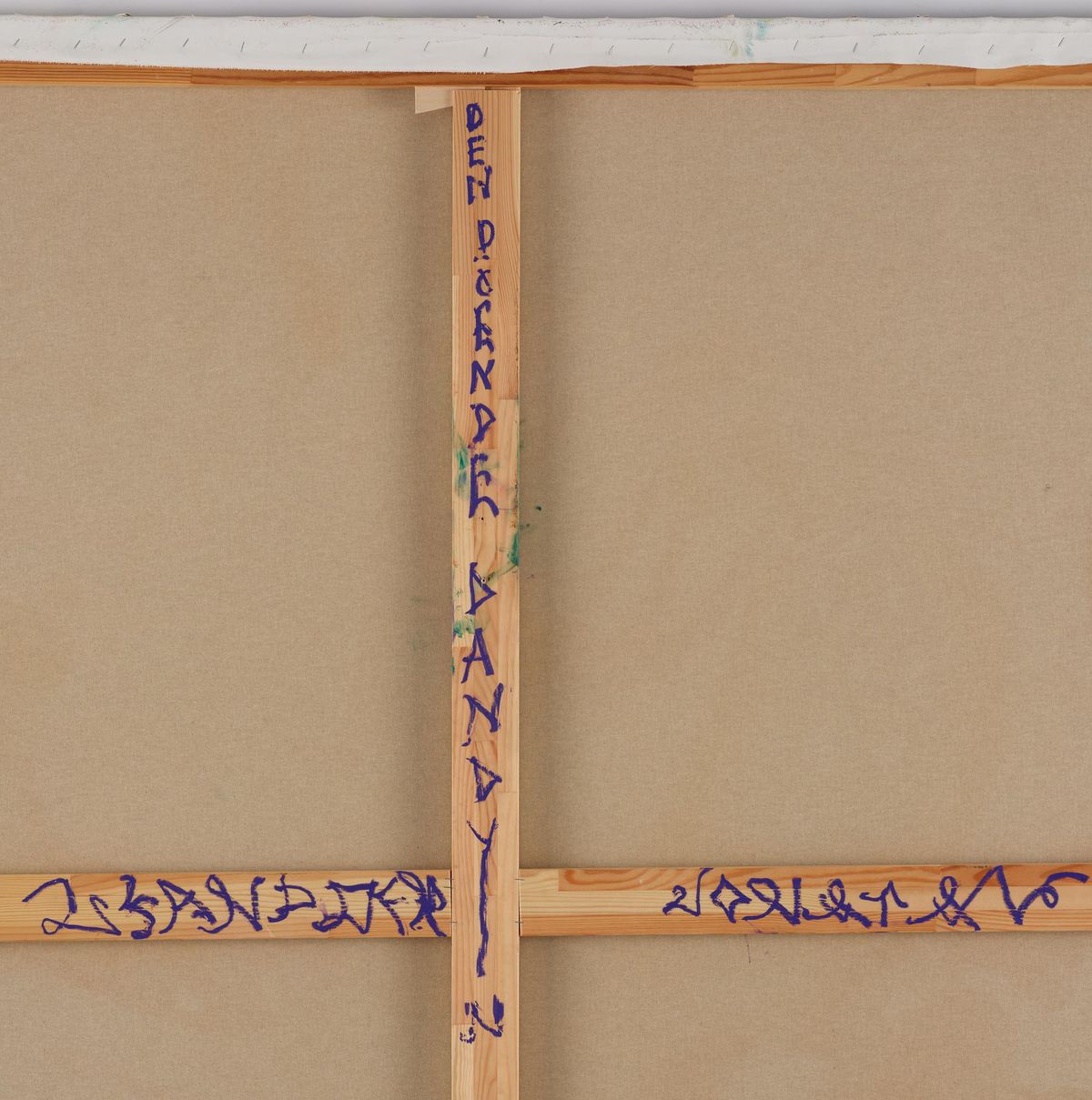 The back of a stretched canvas, raw linen over pale wooden stretcher bars, with the title and a signature written along the bars in thick blue marker.