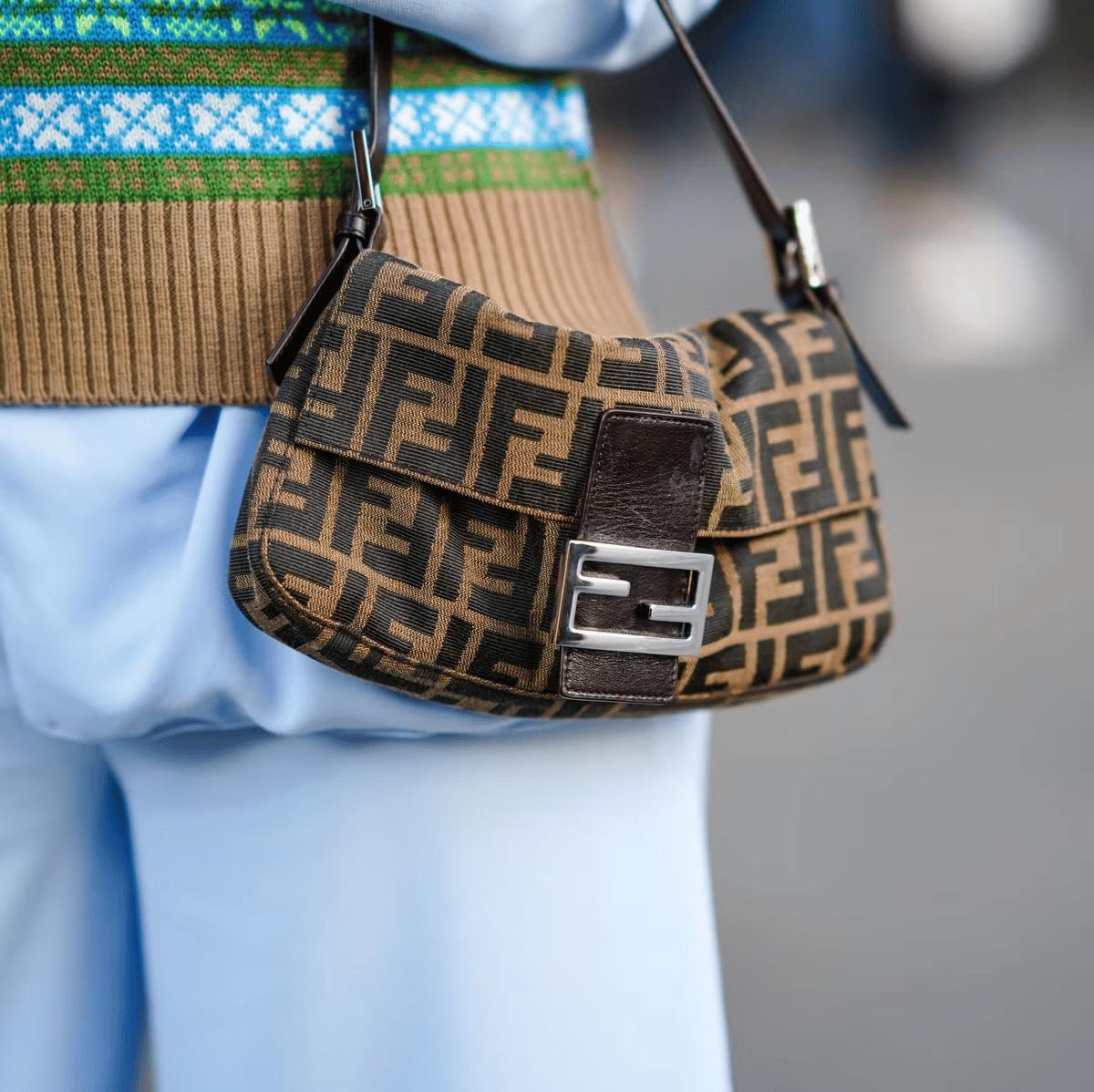  A visual emblem of the 'Deluxe' era: Iconic, logo-driven accessories like the Fendi Baguette became the high-margin engines of corporate luxury, shifting the industry's focus from craftsmanship to mass-market branding. 