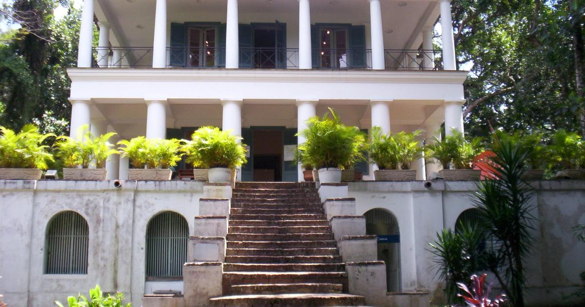 A nineteenth-century neoclassical house with a columned portico on a wooded hillside campus in Rio de Janeiro.