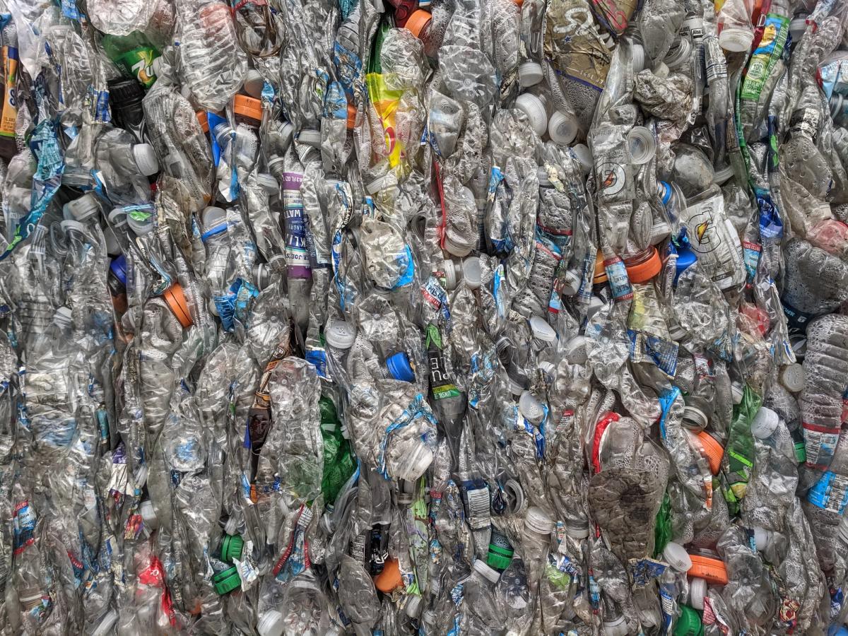 Compressed bales of clear plastic bottles stacked at a recycling facility.