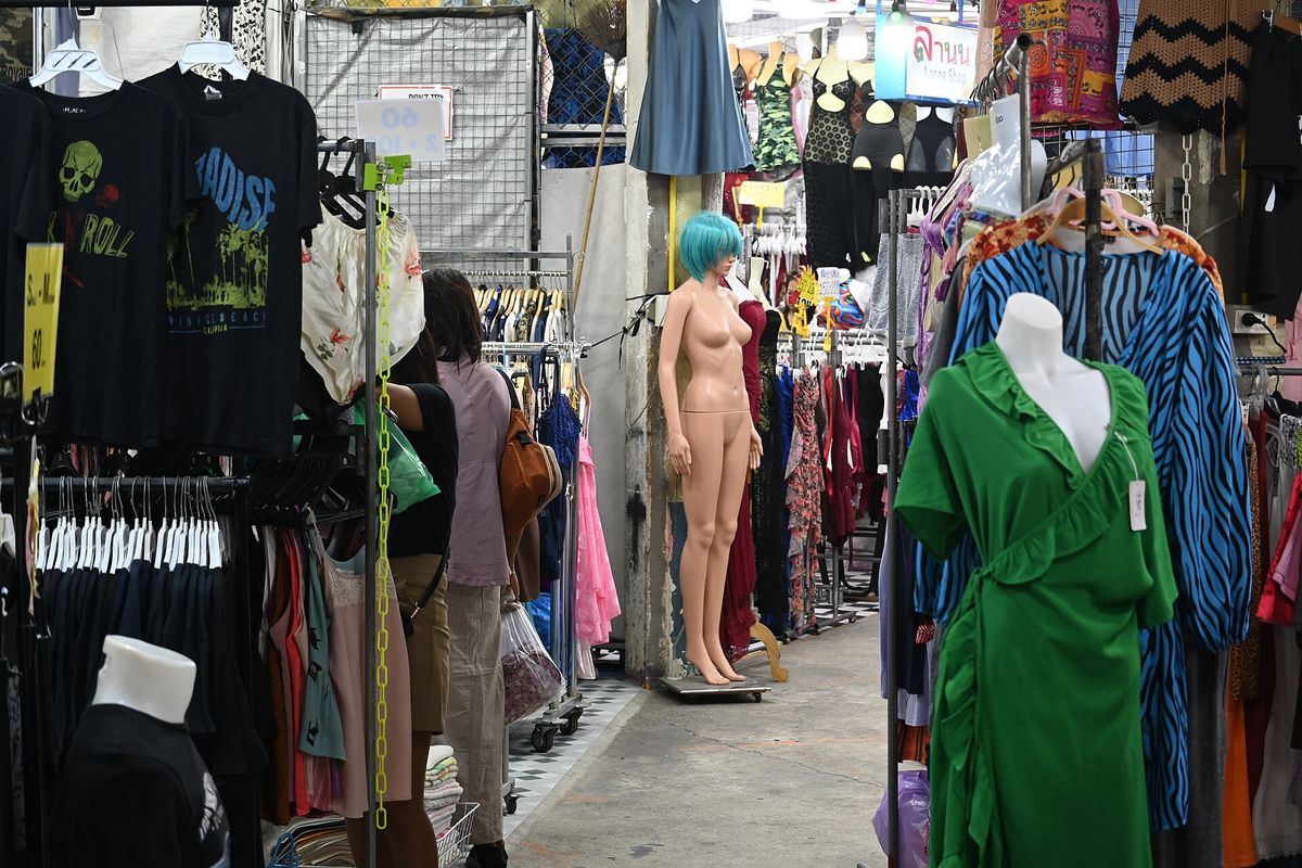 A market aisle lined with densely packed clothing racks and mannequins, the volume the garment system produces.