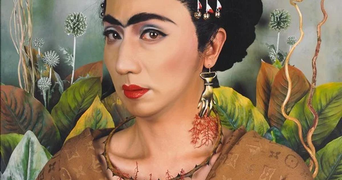 A painting of a figure with red and white flowers pinned into braided black hair, a thorn necklace at the throat and a brown shawl covered in a repeating luxury monogram, against large green leaves.