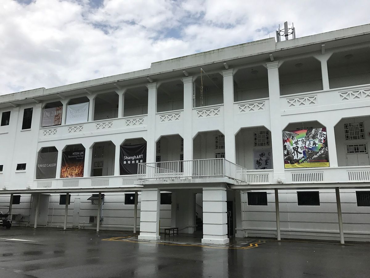 Block 9 at Gillman Barracks, Singapore: a white colonial-era barracks building carrying the banners of several art galleries, with no figures in the frame.