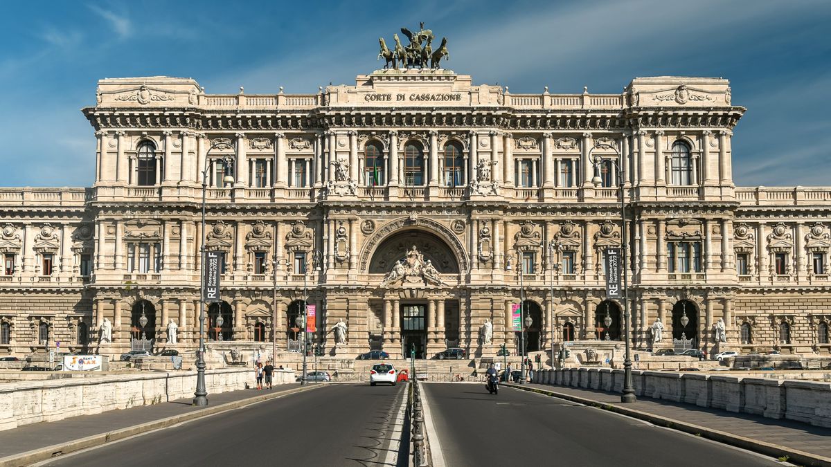 The Palace of Justice in Rome, seat of the Court of Cassation, a vast white stone building on the Tiber under a clear sky.
