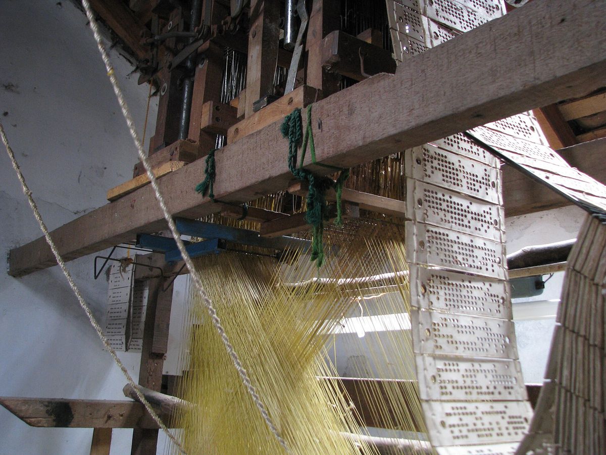 A hand loom for silk weaving in Kanchipuram strung with yellow silk warp threads and Jacquard punch cards.