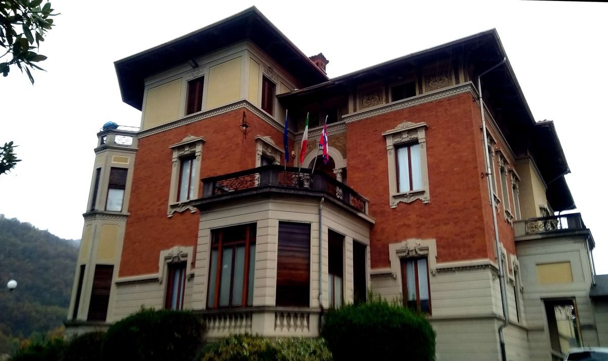 The town hall at Quarona in the Italian province of Vercelli, a pale rendered building behind a low wall.