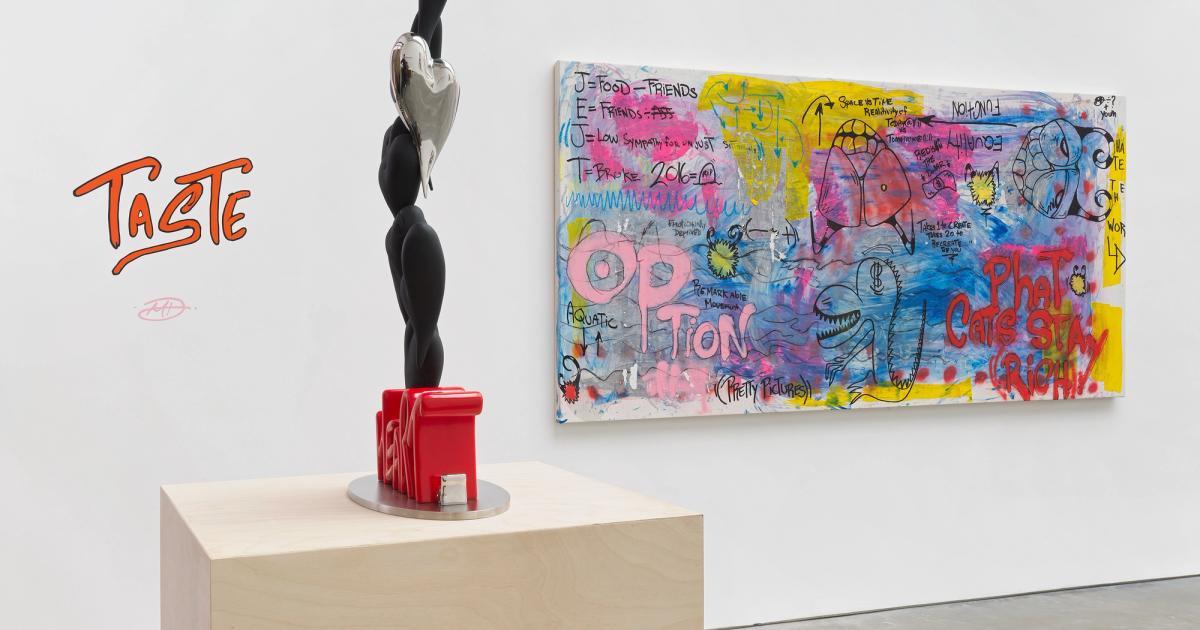 A white gallery wall with the word TASTE hand-lettered in orange and signed beneath it, a tall black and chrome sculpture of stacked forms on a pale wood plinth, and a wide painting covered in handwriting and cartoon mouths hung to the right.